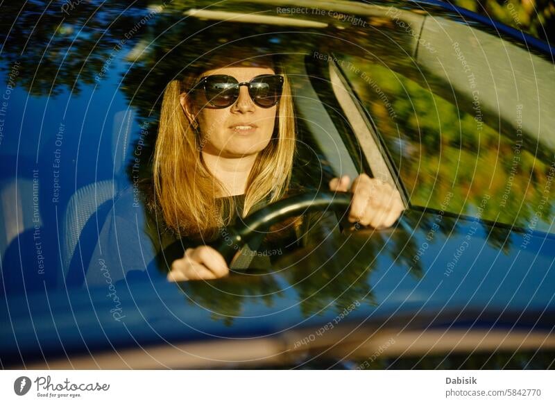 Eine glückliche Frau sitzt im Auto. Blick durch die Windschutzscheibe PKW Fahrer genießen Glück fahren Fahrzeug achtsam reisen Erwachsener attraktiv schön