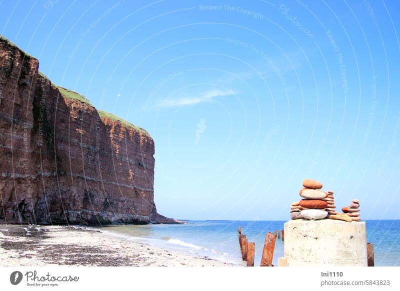 Nordostseite von Helgoland Steintürmchen auf Betonpfeiler schönes Wetter Insel Nordsee Nordseite Felsen Klippe roter Felsen Meer blauer Himmel Strand