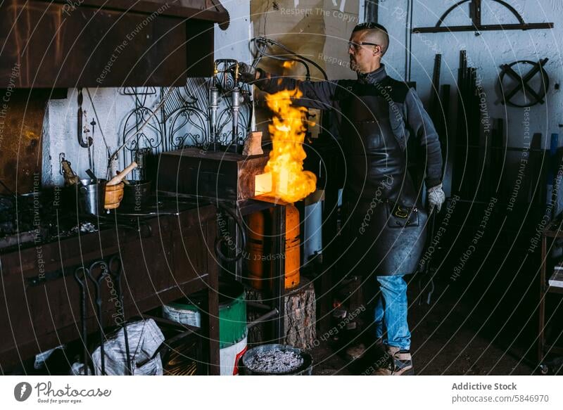 Schmied bei der Arbeit mit geschmolzenem Metall in der Schmiede Hufschmied männlich schmieden Werkstatt Feuer Gerät Beruf Handwerk Brand erwärmen Kunstgewerbler