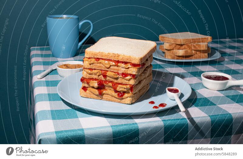 Stapel von PB und Jelly Sandwiches gerade serviert, mit einer Tasse eines amerikanischen Kaffee und einige Brotscheiben in einem blauen Hintergrund Frühstück