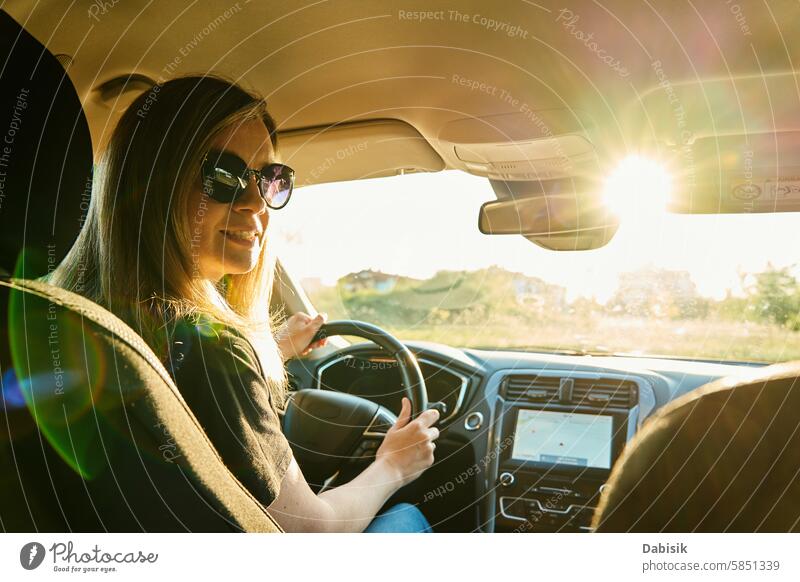 Frau mit Sonnenbrille fährt Auto mit Sonnenlicht durch die Windschutzscheibe fahren PKW Fahrer sonnig Lenkrad Fahrzeug Lächeln Tageslicht Autoreise ländlich