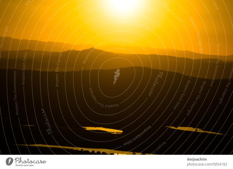 Die Abendsonne erstrahlt über den Bergen in einem sehr  intensiven Orange.. Sonnenuntergangslandschaft Sonnenuntergangshimmel Sonnenlicht Himmel Abendstimmung