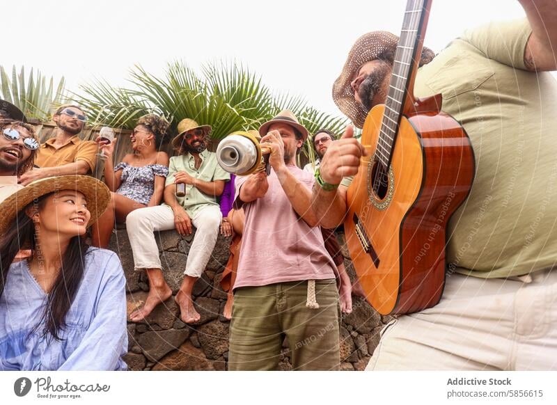 Eine bunt gemischte, fröhliche Gruppe von Menschen, die eine Party mit Live-Musik im Freien genießen Freunde Gitarre Lachen rassenübergreifend vielfältig