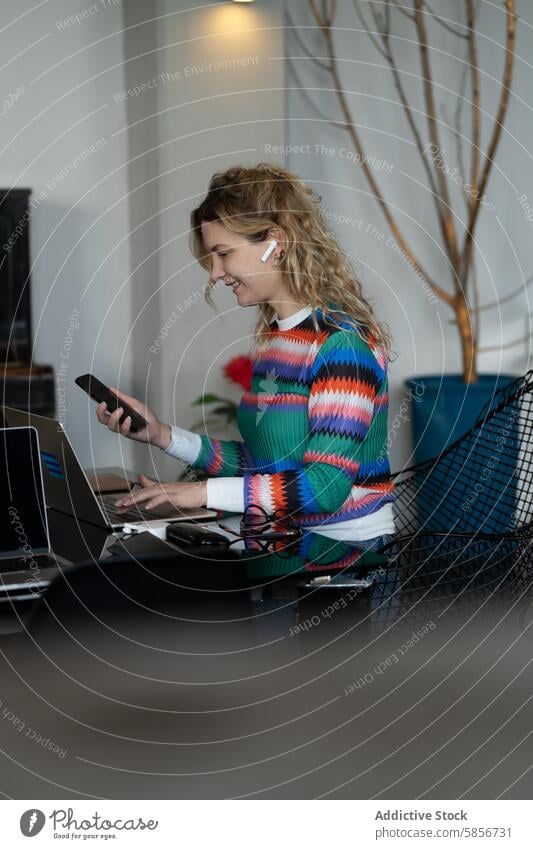 Junge Frau arbeitet aus der Ferne mit Laptop und Smartphone professionell Fernarbeit Heimarbeitsplatz jung arbeiten Technik & Technologie modern Lifestyle