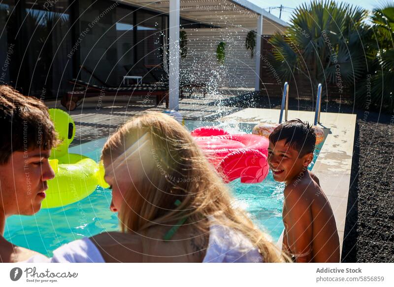 Familienspaß mit Geschwistern im Schwimmbad Mädchen Jungen die sich gegenseitig ansehen Genuss Wasser platschen sonnig im Freien Sommer Freizeit Beckenrand