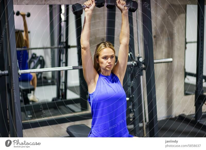 Frau beim Training mit Hanteln in einem Fitnessstudio blond Kaukasier jung Schönheit sportlich Übung Athlet Gesundheit Stärke aktiv Muskel Energie Wellness