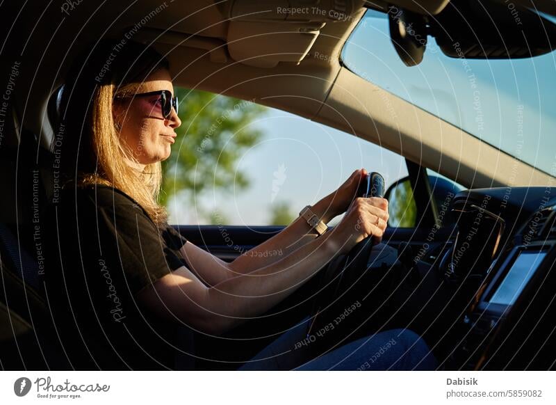 Eine glückliche Frau sitzt im Auto. Blick durch die Windschutzscheibe PKW Fahrer genießen Glück fahren Fahrzeug achtsam reisen Erwachsener attraktiv schön