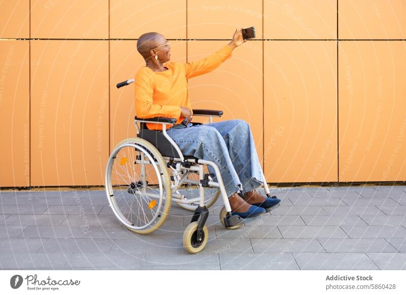 Geschäftsfrau im Rollstuhl macht ein Selfie im Freien Selbstständigkeit Technik & Technologie orange Hintergrund modern pulsierend Zugänglichkeit Mobilität