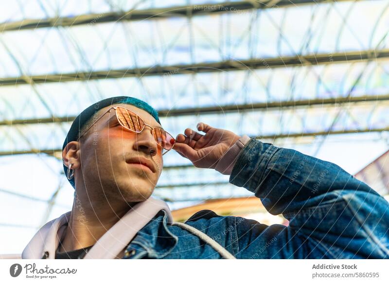 Stilvoller junger Mann mit blauem Haar und roter Sonnenbrille in städtischer Umgebung blaue Haare rote Sonnenbrille urban trendy stylisch Großstadt lässig