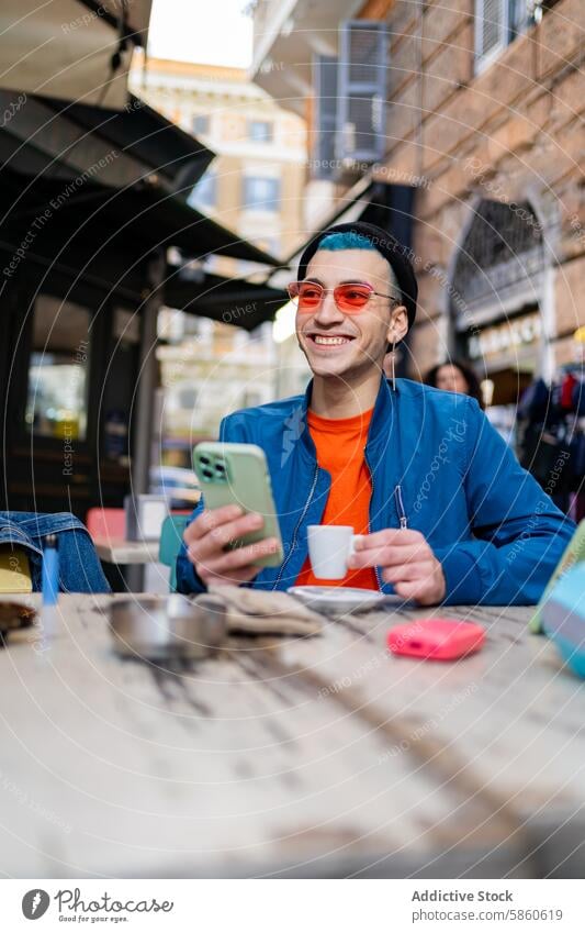 Junger Mann genießt Kaffee und Smartphone in einem Straßencafé jung im Freien Café Sonnenbrille urban Lifestyle verbinden Tasse Tisch Lächeln Glück Freude