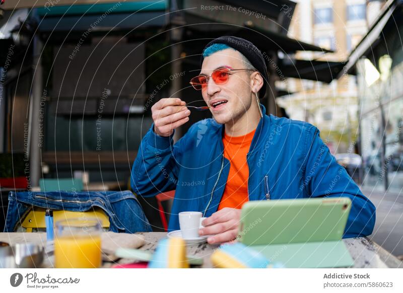 Stilvoller junger Mann beim Frühstück in einem Stadtcafé Großstadt Café Essen stylisch im Freien Tablette Espresso blaue Jacke orangefarbenes Hemd trendy Mode