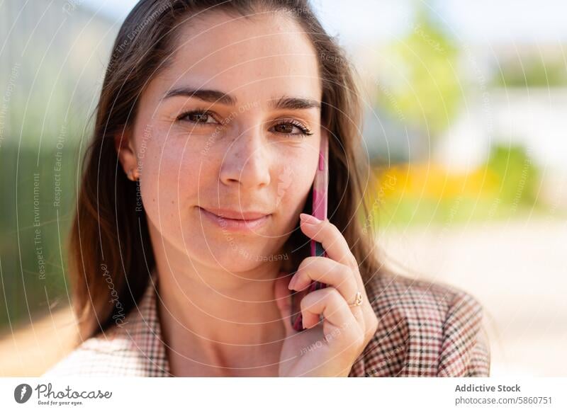 Frau spricht mit einem rosa Handy im Freien Mobile Telefon sprechend Mitteilung natürlich Hintergrund verschwommen Lächeln jung Gerät Apparatur Gespräch