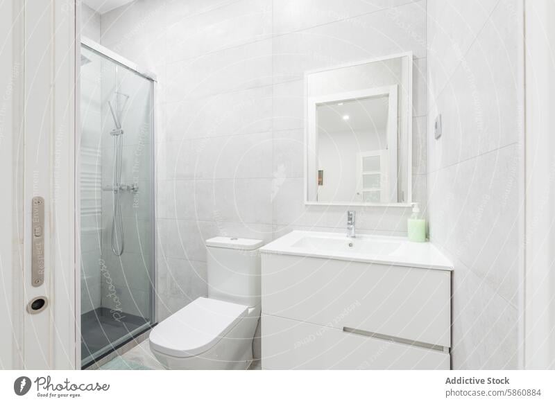 Modernes Badinterieur mit Dusche und weißen Schränken Innenbereich Design modern Sauberkeit Waschtisch Kabinett Glas Spiegel Toilette grau Fliesen u. Kacheln