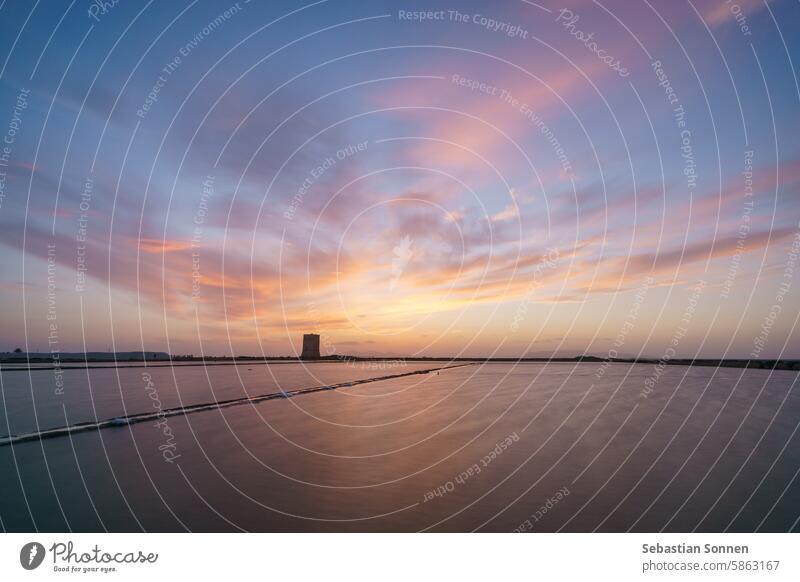 Leuchtender Himmel in der Abenddämmerung nach Sonnenuntergang im Naturschutzgebiet Saline di Trapani mit Salzfeldern und Torre Nubia, Contrada Nubia, Sizilien, Italien