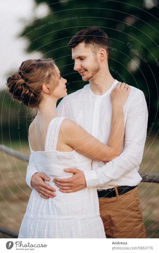 Mädchen in einem weißen Sommerkleid und ein Mann in einem weißen Hemd bei einem Spaziergang bei Sonnenuntergang mit einem Blumenstrauß braun Tag Erde Wald