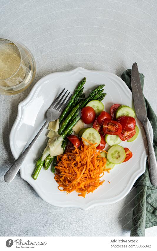 Gesundes vegetarisches Gericht mit Spargel und geriebenen Möhren Tomate Salatgurke Käse Gesundheit Vegetarier Mahlzeit Teller weiß Utensil Gabel Messer nahrhaft