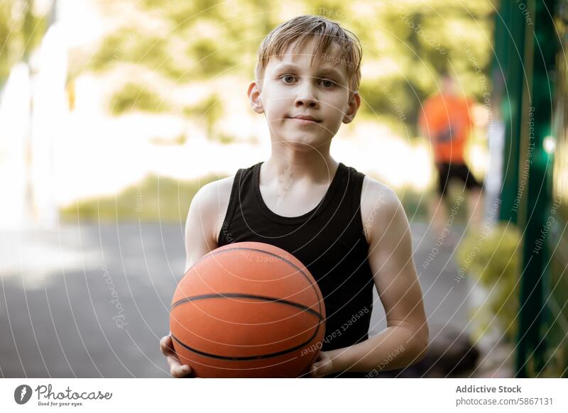 Jugendlicher hält Basketball im Freien Teenager Junge sportlich Sport Tanktop Park Sommer Fitness Aktivität Spiel Ball lässig Übung Lifestyle Training jung