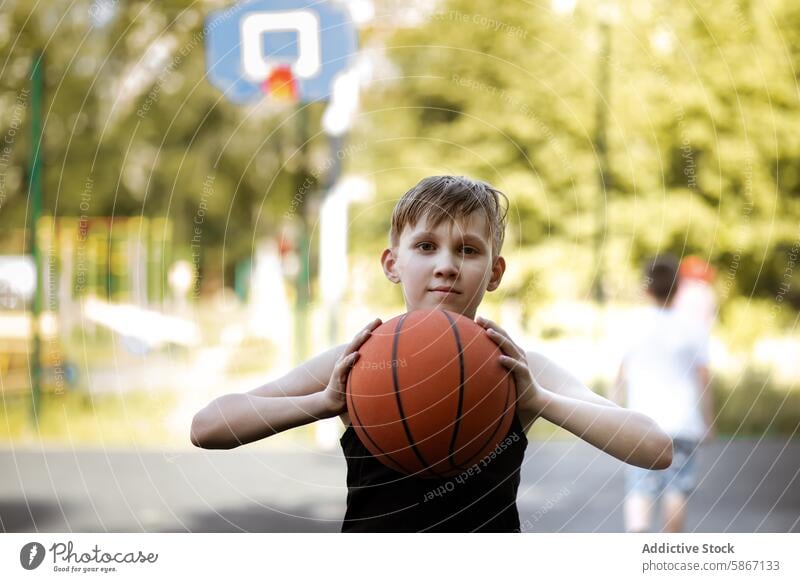 Kleiner Junge hält einen Basketball auf einem Platz im Freien Teenager Sport Sommer aktiv Freizeit Spiel Gericht spielen Fitness Gesundheit Erholung Jugend