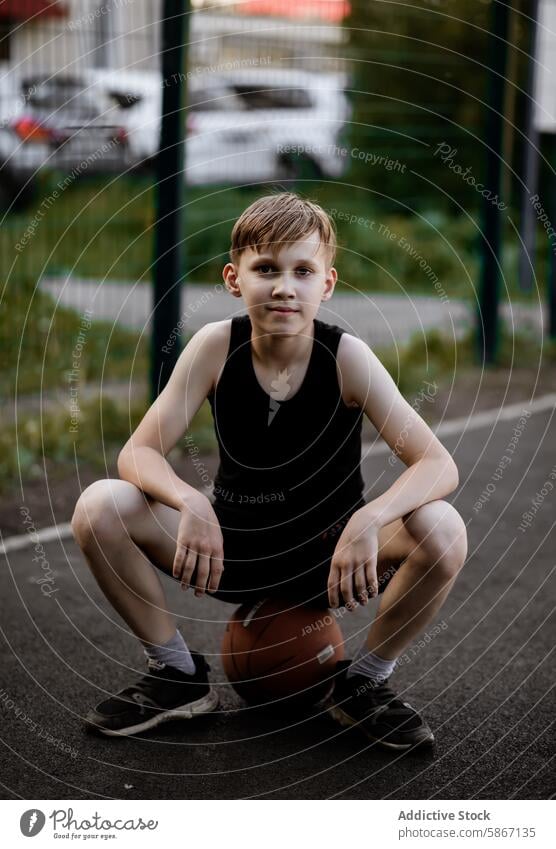 Teenager macht eine Pause vom Basketballspielen im Freien Sport aktiv jung männlich Park Sitzen fokussiert sportlich Fitness Jugend Erholung lässig Sommer