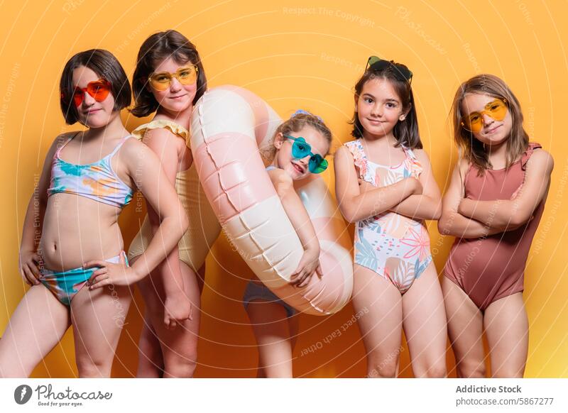 Gruppe von Kindern in Badekleidung mit Sommerrequisiten im Studio Atelier Thema Badebekleidung farbenfroh Sonnenbrille Poolschwimmer freudig pulsierend