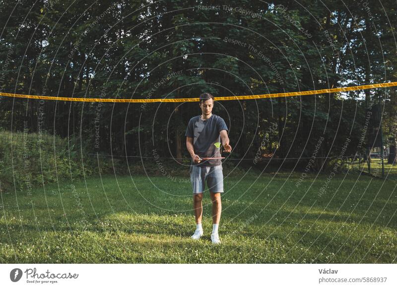 Ein schwarzhaariger Badmintonspieler übt seine Schläge auf dem Rasenplatz. Individuelles Techniktraining. Das Amateurkonzept des Sports. Die Freude am Spiel