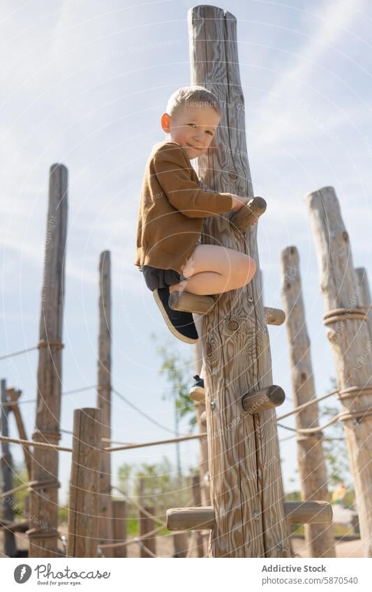 Kleiner Junge klettert im Sommer auf einem Spielplatz Klettern im Freien Spaß Aktivität freudig Kind hölzern Struktur Park spielen Erholung aktiv Abenteuer