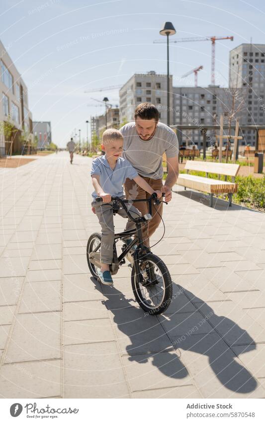 Vater bringt Sohn im Stadtpark das Fahrradfahren bei Park Mitfahrgelegenheit Lehre urban Lernen männlich Erwachsener Kind Sommer im Freien Großstadt Aktivität