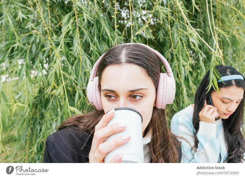 Junge Studenten genießen Musik und Getränke in der Natur Schüler Freund Kopfhörer trinken im Freien jung Smartphone Frau Grün sich[Akk] entspannen Freizeit