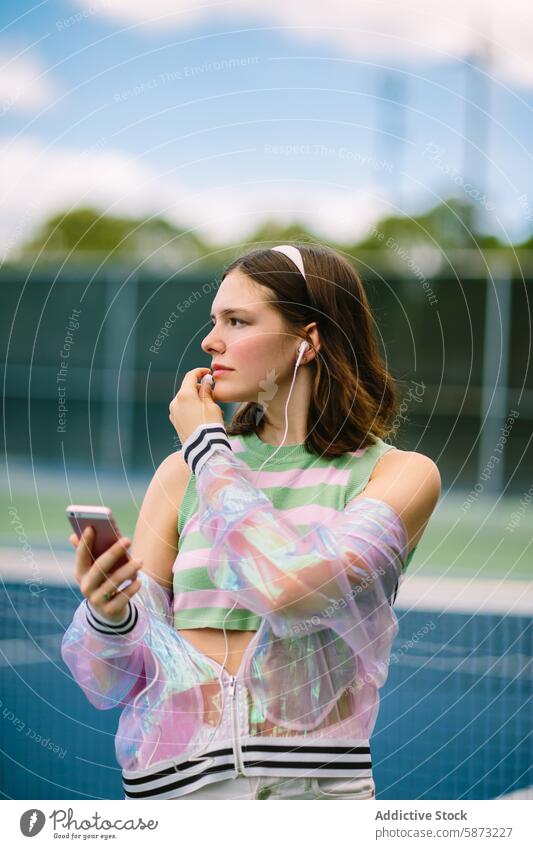 Junge Frau genießt Musik auf dem Smartphone auf dem Tennisplatz Kopfhörer lässig sportlich Kleidung jung hören Beteiligung im Freien Freizeit Aktivität