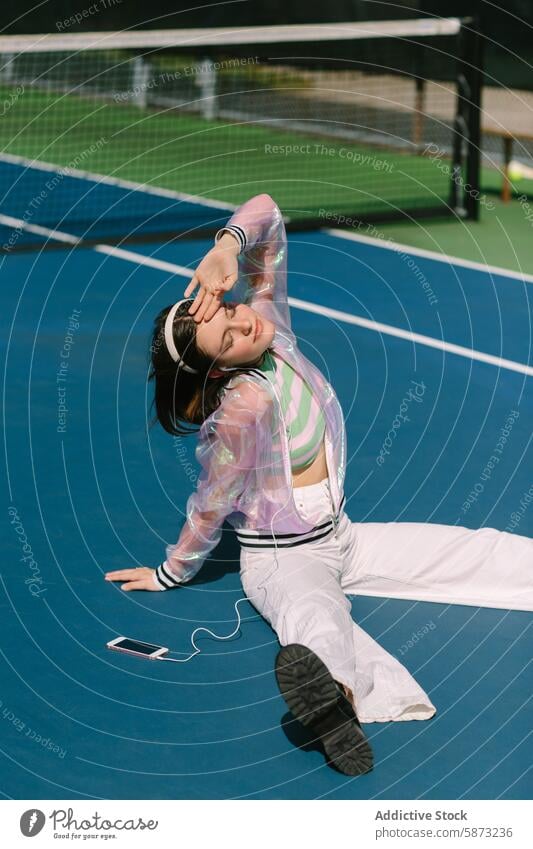 Junge Frau genießt Musik auf einem sonnigen Tennisplatz jung Freizeit Kopfhörer Smartphone Freude Erholung Lifestyle pulsierend Genuss sonniger Tag