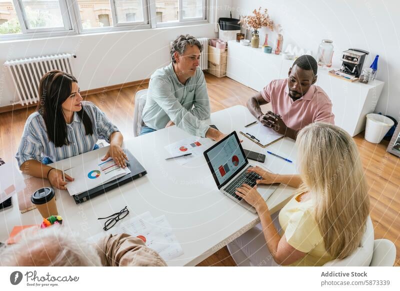 Ein vielseitiges Team arbeitet in einem modernen Coworking Space zusammen Zusammenarbeit professionell vielfältig multiethnisch Laptop Business Tabelle