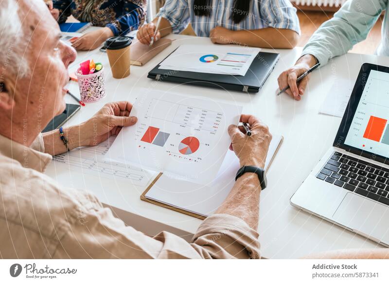 Anonyme Gruppe von Fachleuten in einem Coworking Space, die Diagramme analysieren professionell Menschengruppe Besprechung Daten Tabelle Analyse Laptop