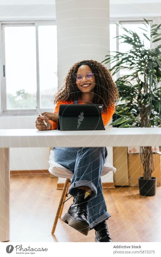 Afroamerikanische Frau benutzt Tablet in einem Coworking Space Afroamerikaner Tablette Griffel Lächeln in die Kamera schauen lässig Büro Zimmerpflanze entspannt