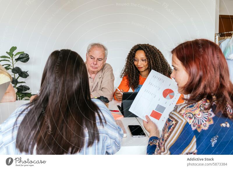 Vielfältiges Team bespricht Strategie im Coworking Space Besprechung Zusammenarbeit professionell Diagramm Afroamerikaner Kaukasier Mann Frau Kollege