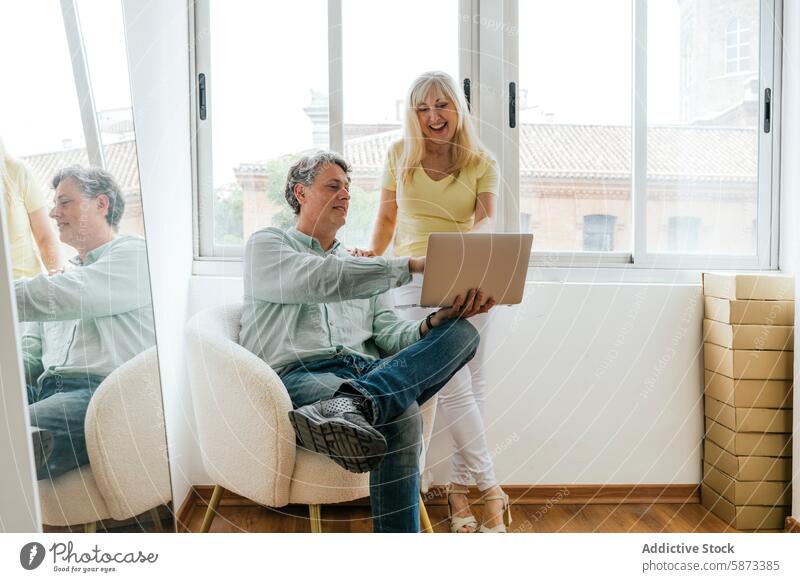 Älteres Paar arbeitet zusammen mit einem Laptop in einem hellen Raum reif arbeiten Coworking Kaukasier Armsessel Fenster Senior Technik & Technologie Apparatur