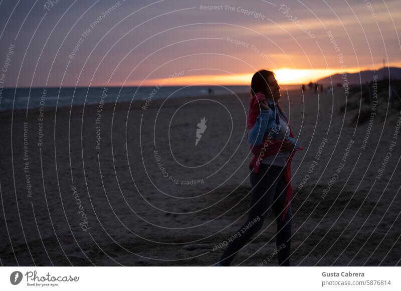 Eine Frau genießt den Sand des Mittelmeers, während die Sonne untergeht. genießen Sandstrand Sonnenuntergang Sonnenuntergangslicht Strand