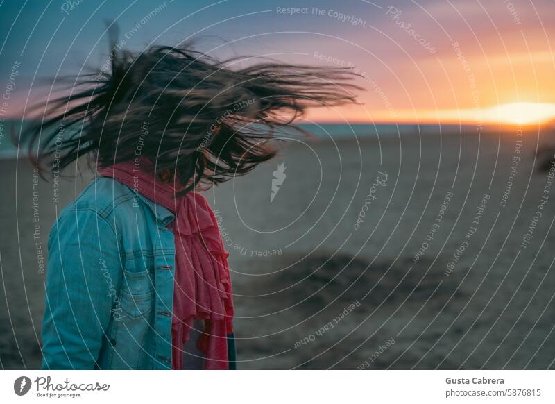 Das Haar der Frau bewegt sich bei Sonnenuntergang am Strand im Wind. Frauenkopf Sand Sandstrand Sonnenlicht Ferien & Urlaub & Reisen Behaarung Farbfoto