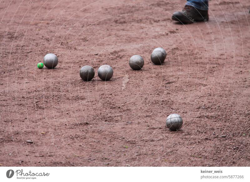 Boule oder Pétanque auf roter Erde Petanque Kugel Spielen Bouelspiel Petanqueplatz Bouleplatz Metallkugeln Eisenkugeln Fuß Boden Sau Schwein Außenaufnahme