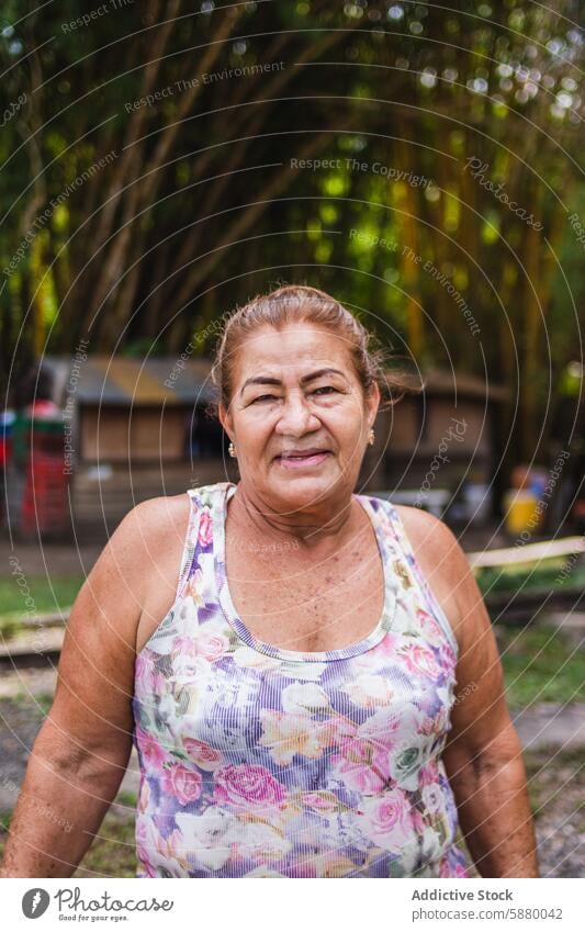 Ältere kolumbianische Frau in einer ländlichen Umgebung älter im Freien Grün Tanktop geblümt selbstbewusst Senior Hintergrund Natur Landschaft Porträt Lächeln