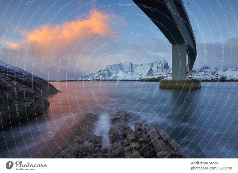 Dramatischer Sonnenuntergang über verschneiten Bergen und einer Brücke auf den Lofoten Landschaft Berge u. Gebirge Schnee Wasser lofoten Norwegen ruhig