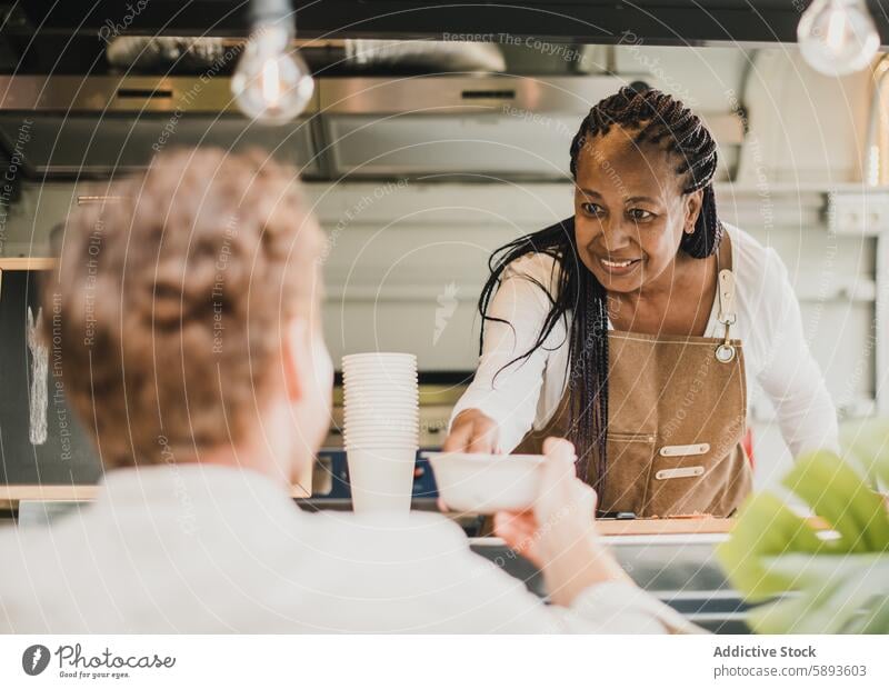 Afrikanische Köchin, die eine Bestellung zum Mitnehmen in einem Imbisswagen serviert - Fokus auf das Gesicht einer älteren Frau Afroamerikaner weg Bar Getränk