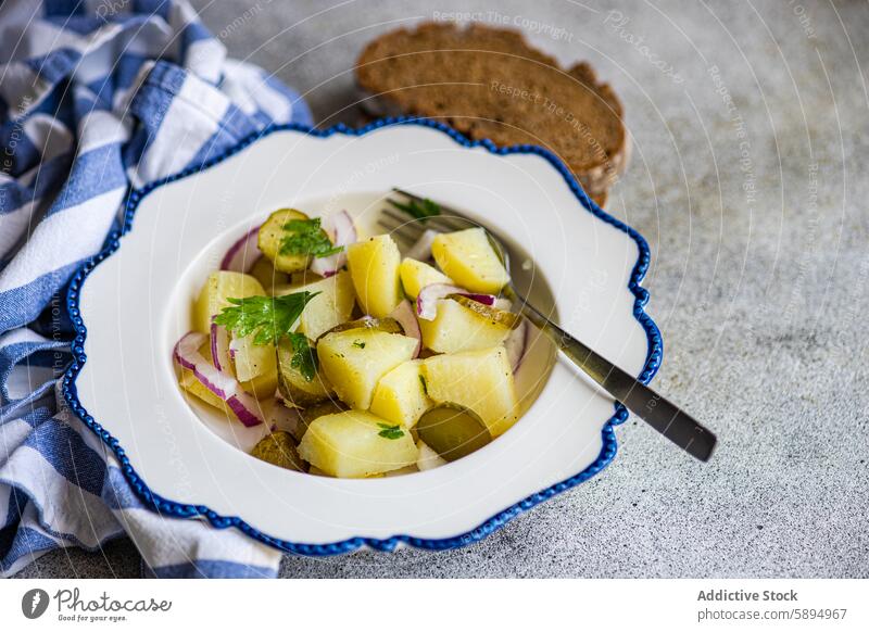 Traditioneller deutscher Kartoffelsalat, serviert mit Brot Salatbeilage Deutsch gekocht Zwiebel fermentiert Salatgurke traditionell Schalen & Schüsseln weiß