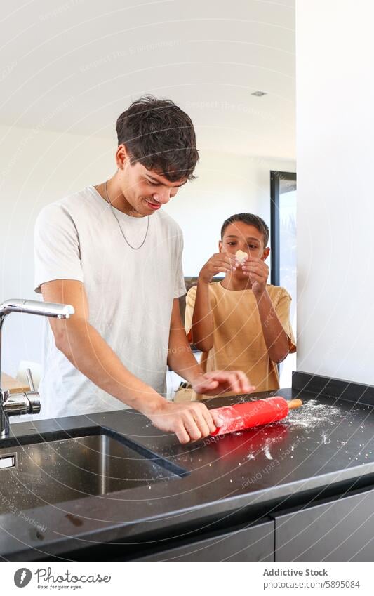 Geschwister kochen gemeinsam in einer modernen Küche Essen zubereiten backen Teamwork Spaß Zeitgenosse Bruder Geschwisterkind Familie Aktivität Nudelholz Mehl