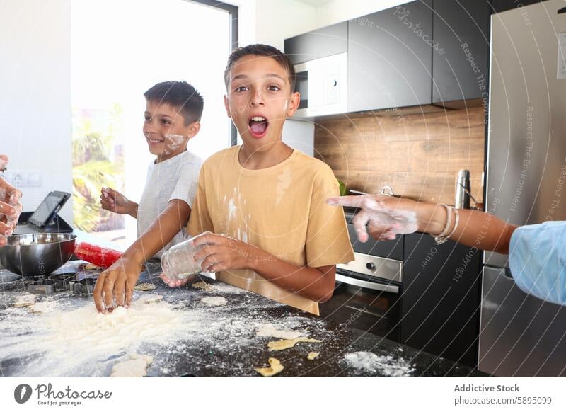 Geschwister haben Spaß beim Backen in der Küche Triplett Bruder backen Essen zubereiten Mehl Freude lachen spielerisch kulinarisch modern Teigwaren