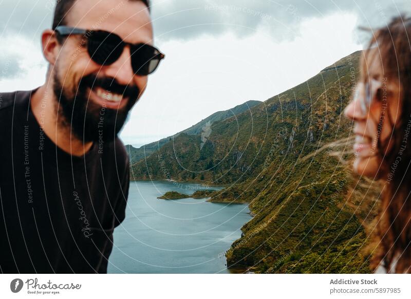 Ein Paar genießt die malerische Aussicht auf einen See in Sao Miguel, Azoren. São Miguel Mann Frau Natur reisen Lächeln Sonnenbrille Ansicht Glück üppig (Wuchs)