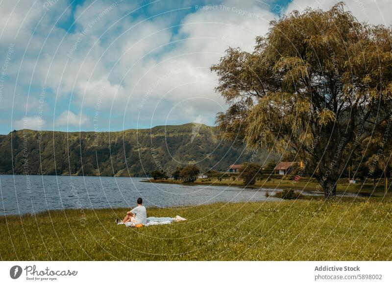 Ein Mann genießt die friedliche Lage am See in Sao Miguel, Azoren. Seeufer São Miguel Ruhe Gelassenheit einsam Grün Hügel Natur männlich Landschaft im Freien