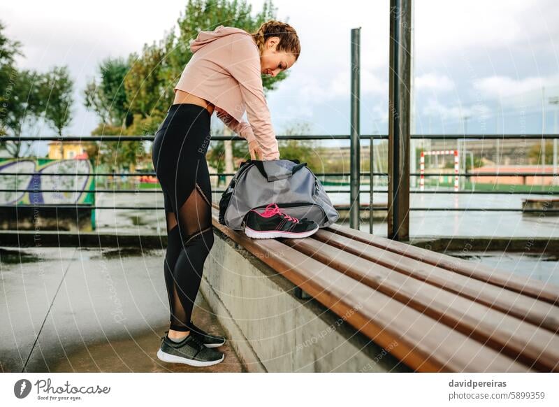 Sportlerin bei der Vorbereitung der Ausrüstung für das Training Athlet vorbereitend Gerät suchend Sporttasche Bank Turnschuh Top Morgen Fitness aktiv attraktiv