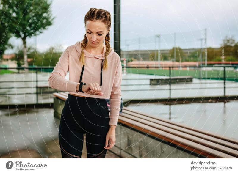 Junge Sportlerin sucht Aktivitätsarmband Frau Athlet Blick smartwatch Schrittzähler Herzschlag Kalorien Textfreiraum Training Morgen Fitness aktiv attraktiv