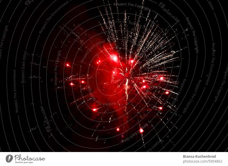 Feuerwerk explodiert in rot am Nachthimmel rotes Feuerwerk Feuerwerkskörper Feuerwerksraketen Explosion Pyrotechnik Feste & Feiern Funken Himmel leuchten Knall