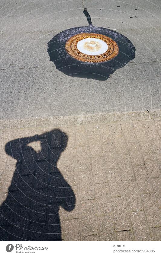 Deckel zu / Schatten einer fotografierenden Person und ein Gullideckel mit Bitumenrand Schattenspiel Straße Verkehrswege Asphalt Straßenverkehr Blog Fotograf